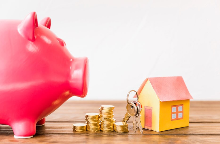 house with key stacked coins besides piggybank